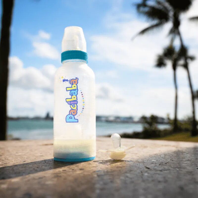 Pacibaba baby bottle with pacifier compartment, standing on a ledge