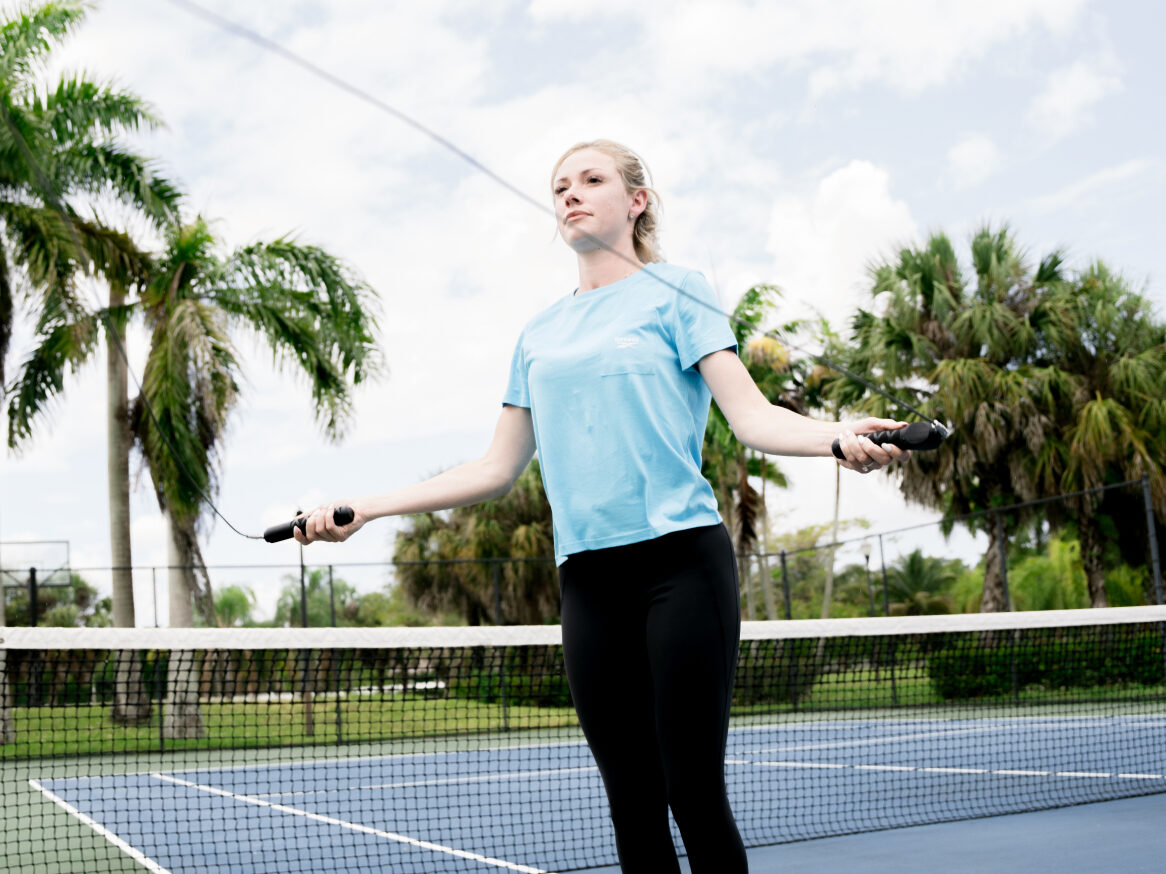 Woman jumping with the Trac Rope smart jump rope on a tennis court